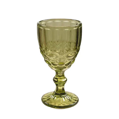 A translucent olive-green glass goblet with embossed patterns and fluted stem complementing decorbites chinoiserie floral birds dinnerware