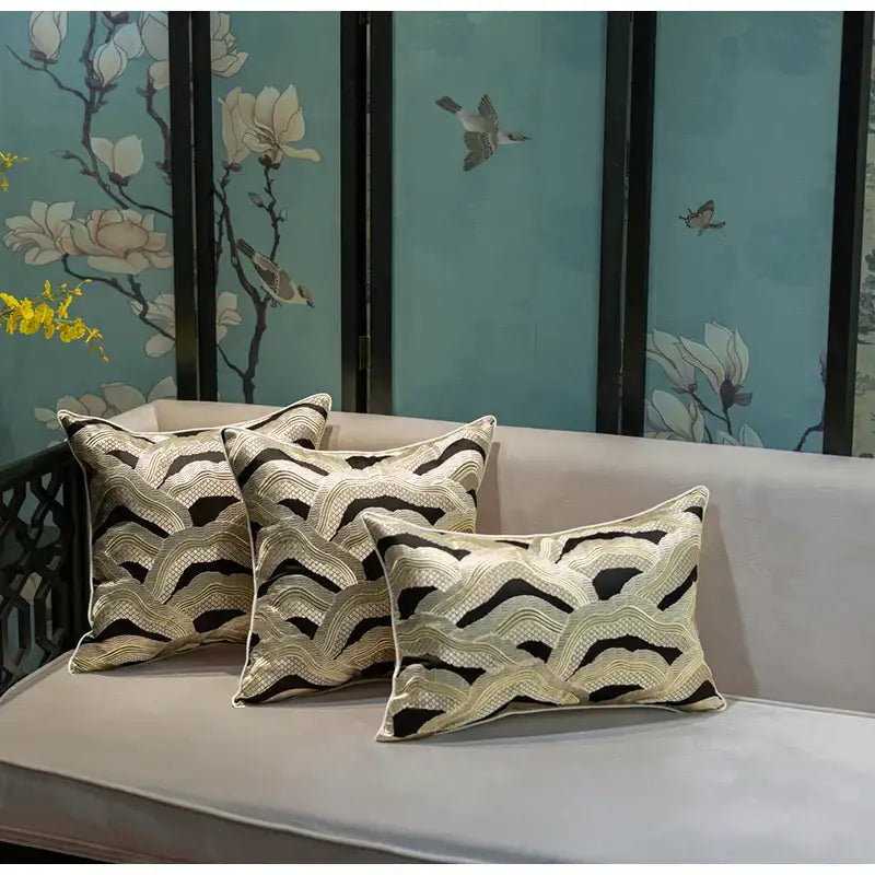 Three elegant black and cream wave-patterned decorbites chinoiserie golden embroidered cushion covers on a light gray sofa