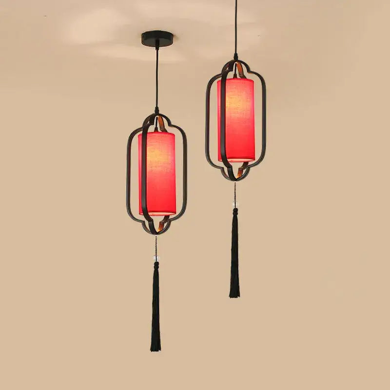 Two elegant black-framed pendant lanterns with glowing red fabric shades and tassels from decorbites chinoiserie retro chandelier