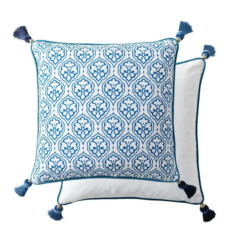 Blue and white patterned square pillow with decorative tassels at each corner.