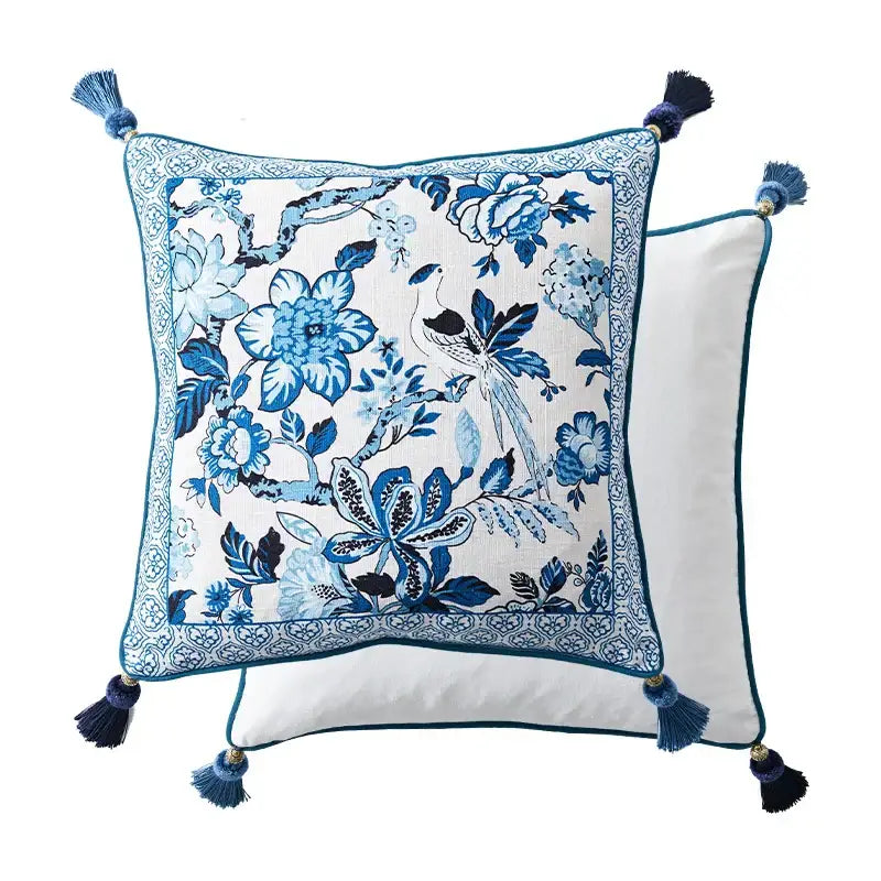 Square lumbar pillow case with chinoiserie style blue floral and porcelain bird embroidery on white fabric with navy tassels