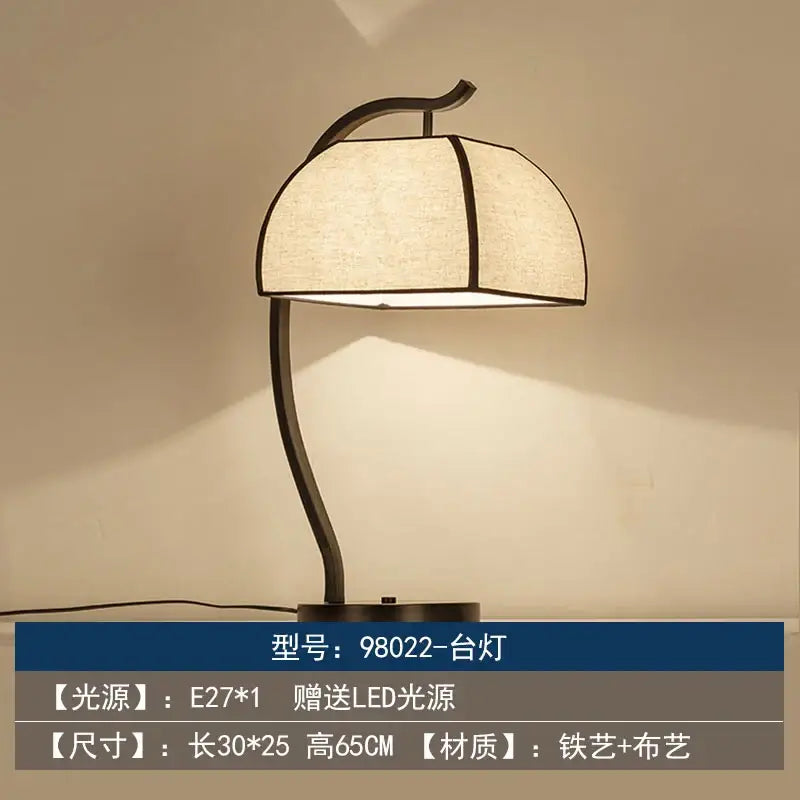 A sleek black iron DecorBites Chinoiserie table floor lamp with a soft beige umbrella-shaped fabric shade