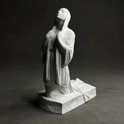 White marble Christian pray sculpture of a praying woman in flowing robes on a rectangular base by DecorBites™
