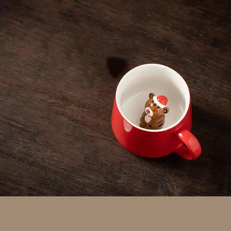 A red porcelain christmas animals ceramic tea cup featuring a brown tiger figurine with a santa hat inside