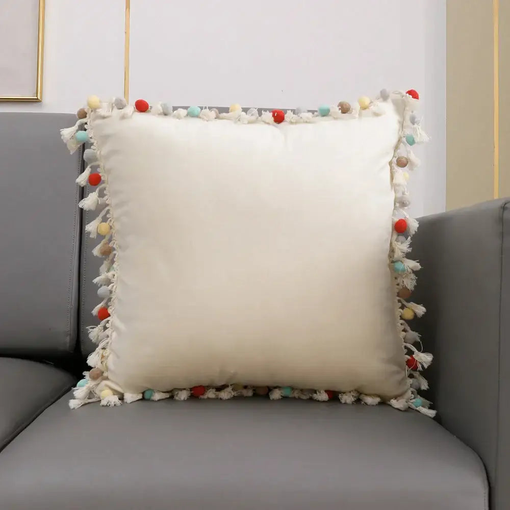 Cream-colored pillow cover with colorful pom-pom tassels from decorbites christmas bell red holiday collection