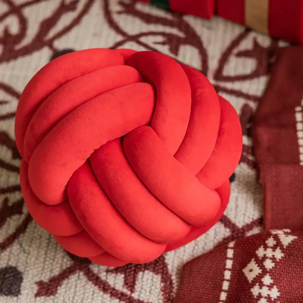 A plush vibrant red knotted toy ball of soft fabric complements decorbites christmas bow patchwork velvet pillow covers