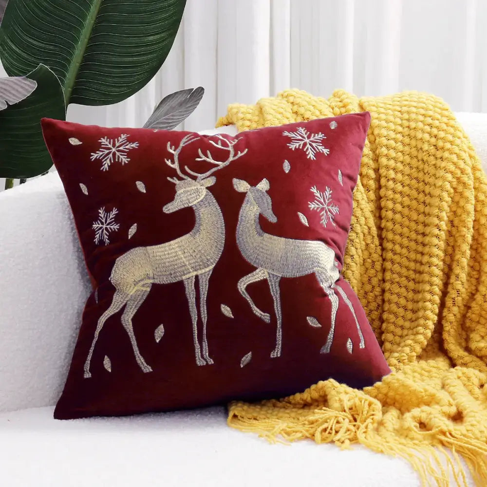 A plush burgundy velvet pillow cover with silver embroidered deer and snowflake patterns from DecorBites Christmas cartoon collection