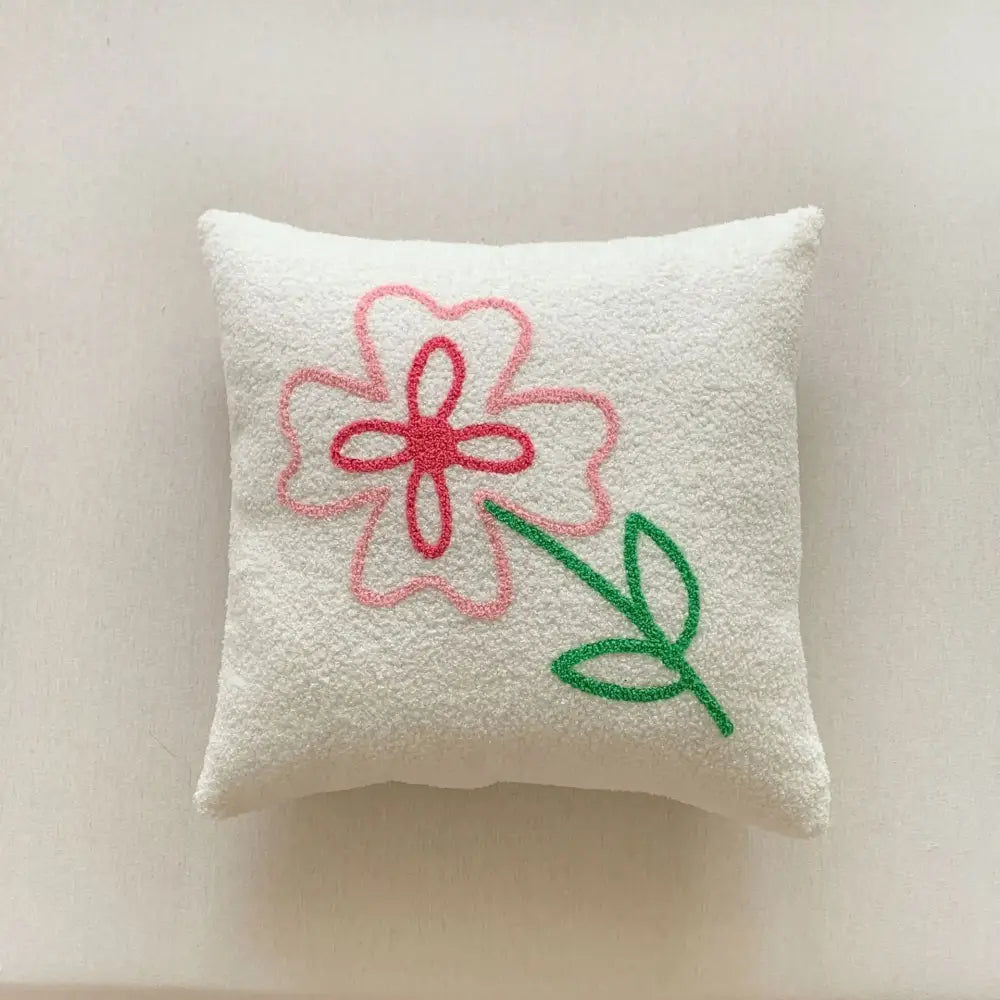 A soft white textured pillow cover with pink flower embroidery from decorbites christmas cartoon collection for festive decor