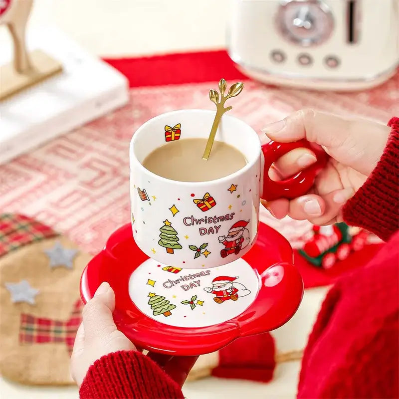 White ceramic christmas ceramic santa tea set with red handle, festive illustrations, matching saucer, and gold leaf spoon