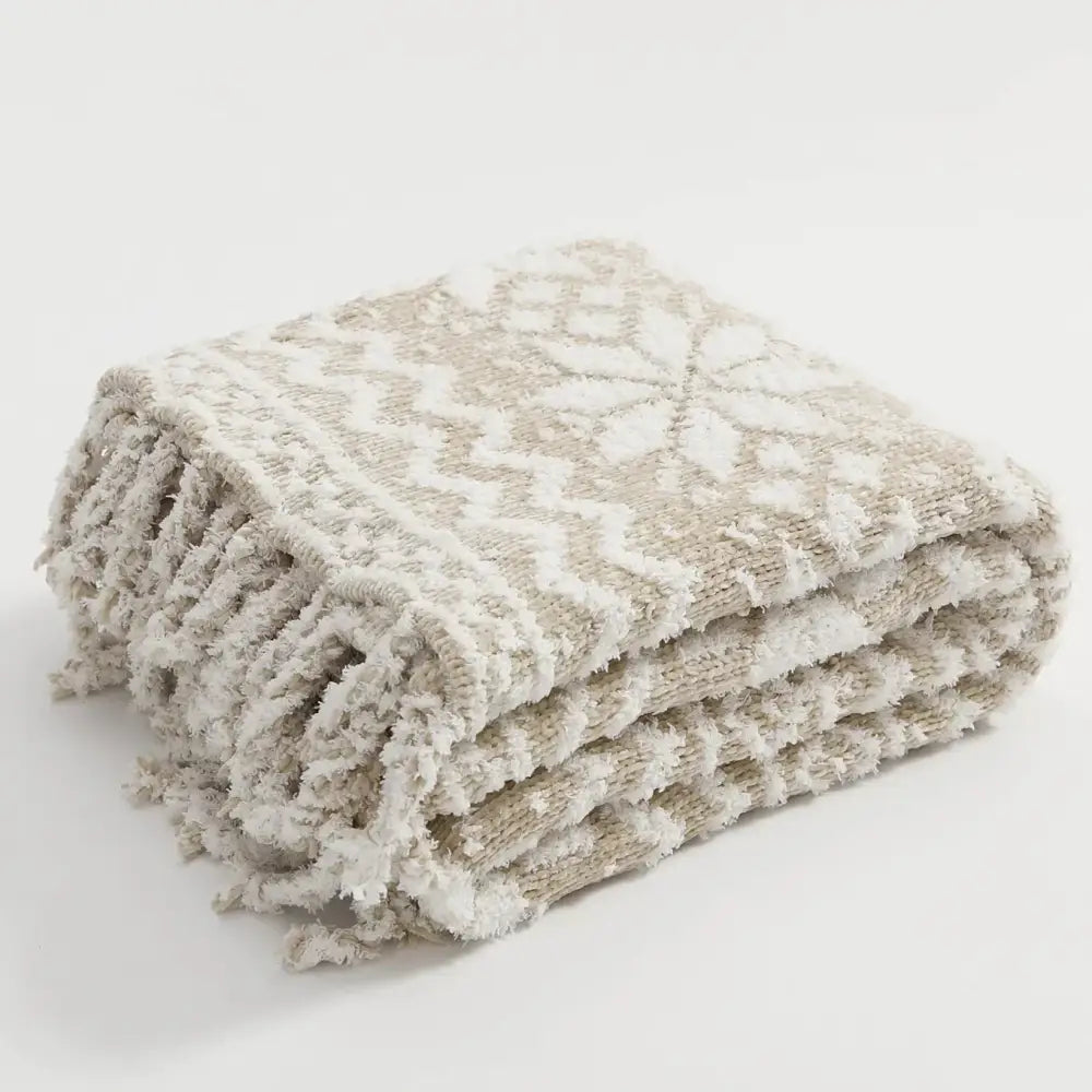 A cozy decorbites christmas chunky knit blanket in beige and cream microfiber with snowflake motifs and fringed edges