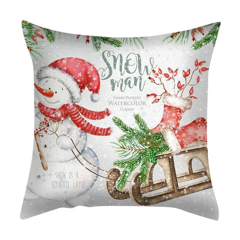 White throw pillow with hand-painted snowman in red santa hat and scarf pulling a sleigh in decorbites christmas cushion set