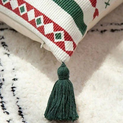 A cozy white cushion cover with red and green geometric embroidery and dark green tassel for DecorBites Christmas decoration