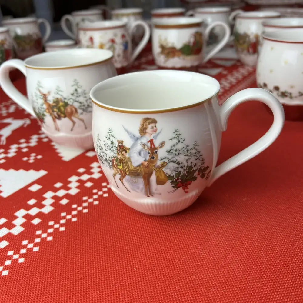 White ceramic christmas mug with gold rim featuring painted angel and deer scene from decorbites christmas dinnerware set