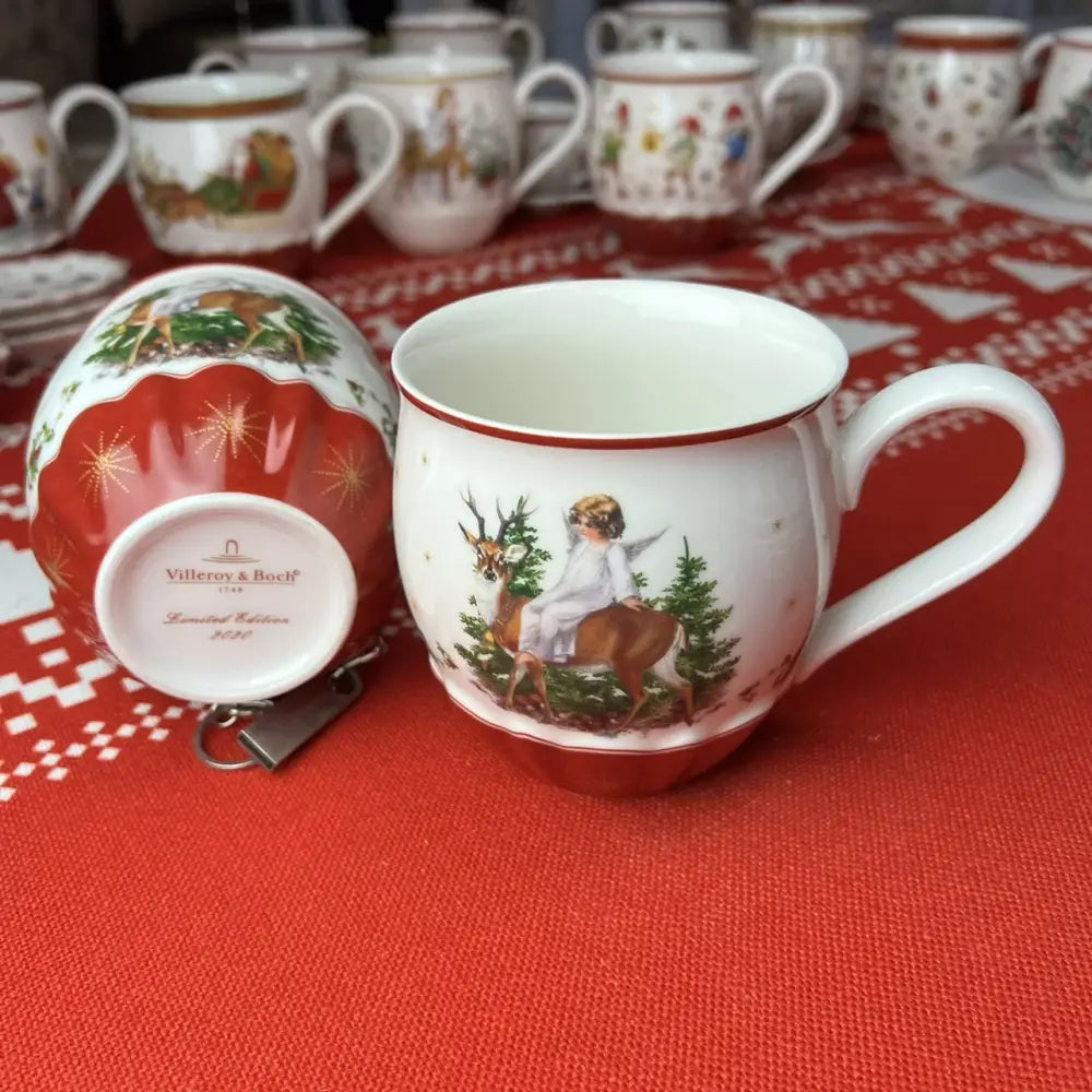 White ceramic mug with red rim and base featuring an angel and deer scene from decorbites christmas dinnerware set