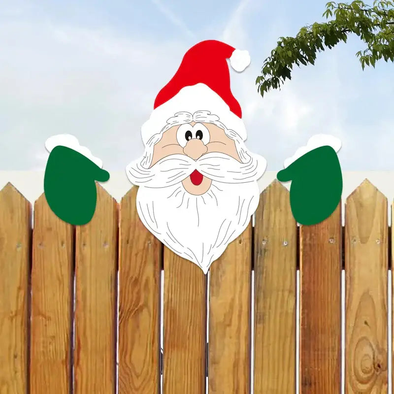 A cheerful red and white santa claus face wooden decoration with green mittens on a fence for decorbites christmas door frame