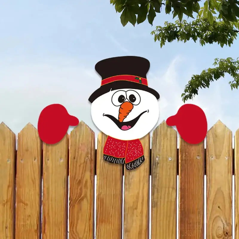 A cheerful cartoon snowman decoration with black top hat and red scarf peeking over a wooden fence in decorbites christmas door frame set
