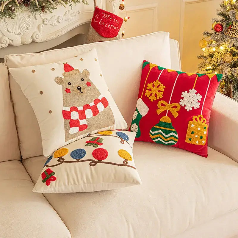 Three festive decorbites christmas embroidered pillow covers featuring a beige bear, red geometric, and cream string lights design