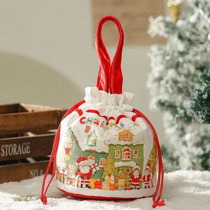 White drawstring decorbites christmas eve apple bag with red handles and festive santa and snow-covered house illustrations