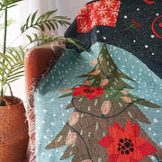 Cozy teal DecorBites Christmas holiday sofa blanket with festive tree, red poinsettias, snowflakes, and frayed edges