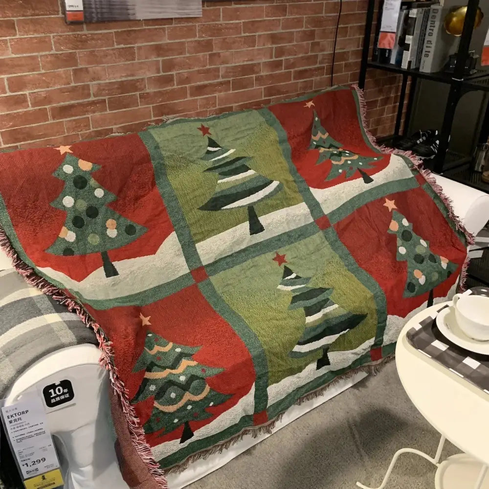 Decorbites christmas holiday sofa blanket in red and green with fringed edges displayed on a couch