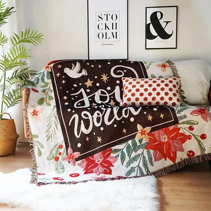 A decorbites christmas holiday sofa blanket with dark brown center text and star motifs bordered by red poinsettias and green foliage