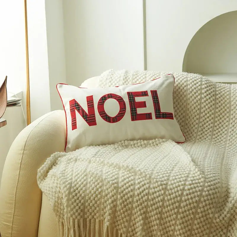 White rectangular pillow with red plaid decorbites christmas letter embroidery spelling noel and matching stitched border