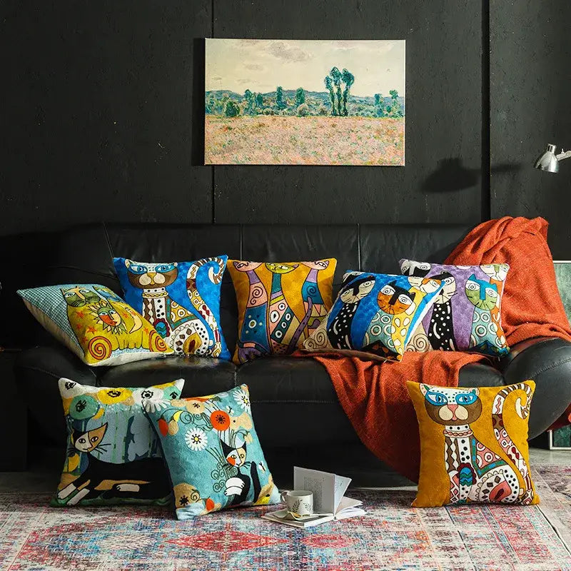 A collection of colorful whimsical cat-themed cushion covers with vibrant patterns on a black leather sofa decorbites christmas picasso style