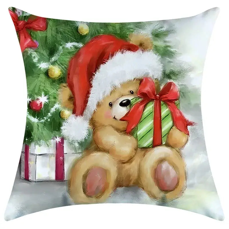 A cozy tan plush teddy bear with a santa hat holding a green gift on a decorbites christmas pillowcase