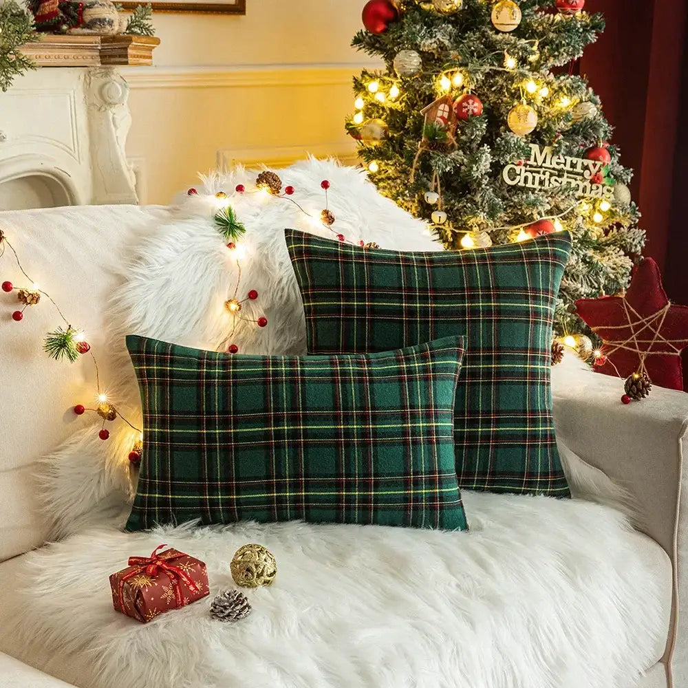 Two green decorbites christmas plaid cushion covers with red and yellow stripes on a white fur couch