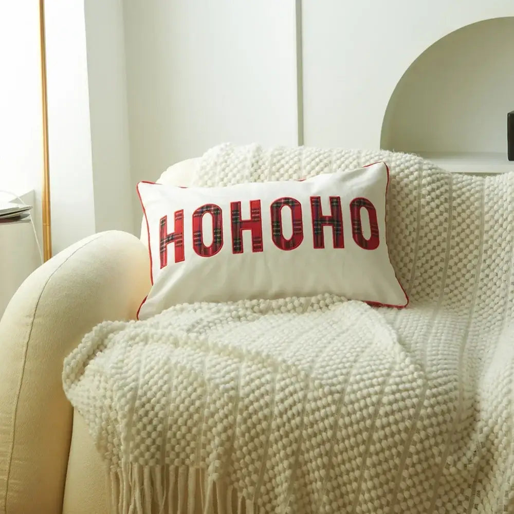 White rectangular decorbites christmas plaid pillow with red ho ho ho lettering and thin red piping edges for holiday decor