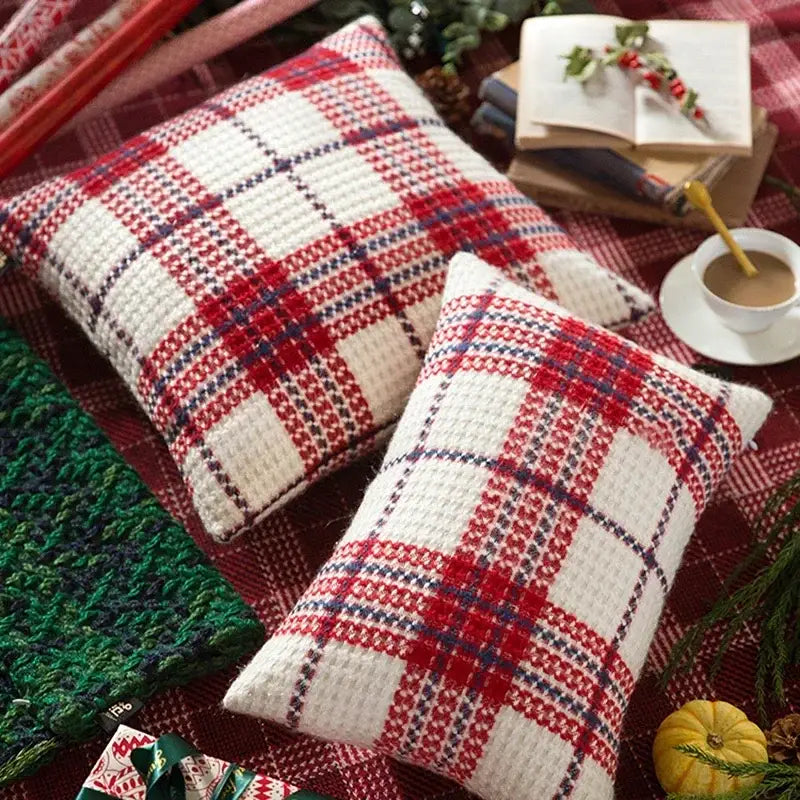 Two square knitted throw pillows with red and white christmas plaid weave cushion covers accented by navy blue lines