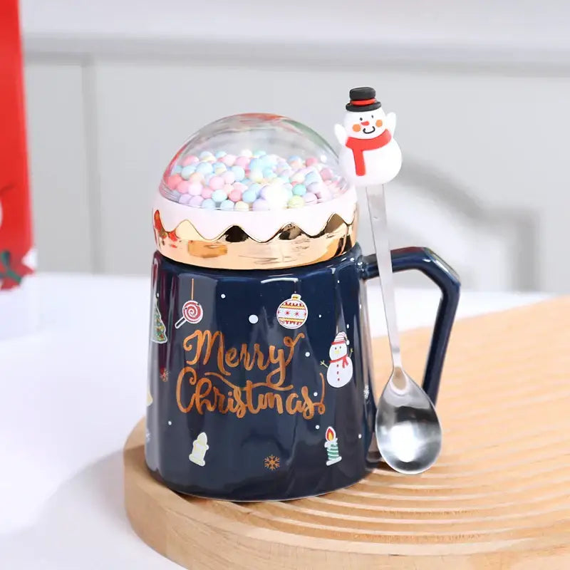 Navy blue ceramic mug with gold merry christmas script and clear dome lid filled with colorful candy spheres from decorbites christmas planet