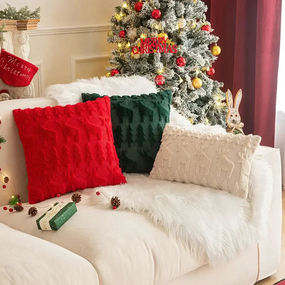 Three decorbites christmas plush throw pillows in red green and cream knit fabric on white couch for holiday decor