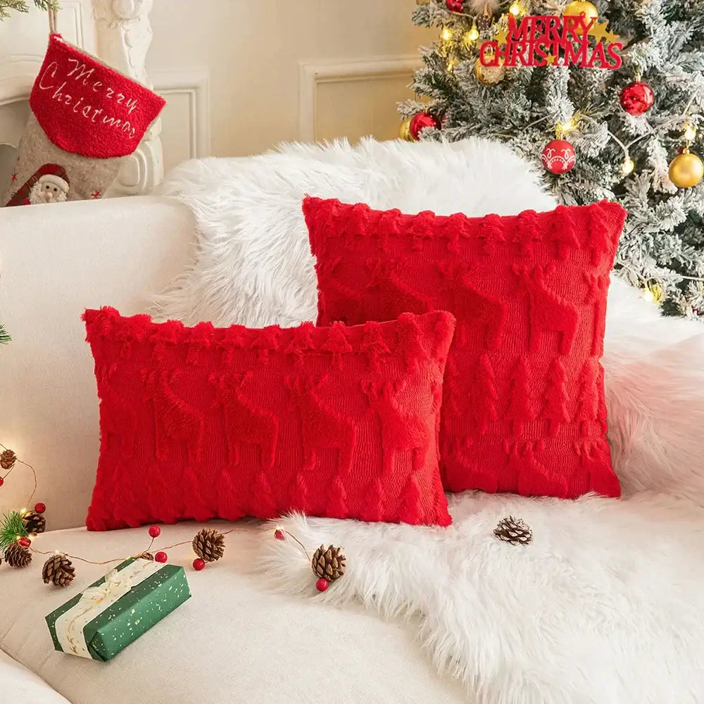 Two vibrant red decorbites christmas plush throw pillows with textured cable knit and frayed edges on white fur blanket