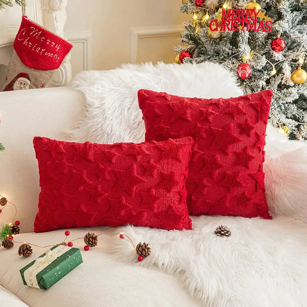 Two vibrant red decorbites christmas plush textured throw pillows with raised star pattern on white fur sofa