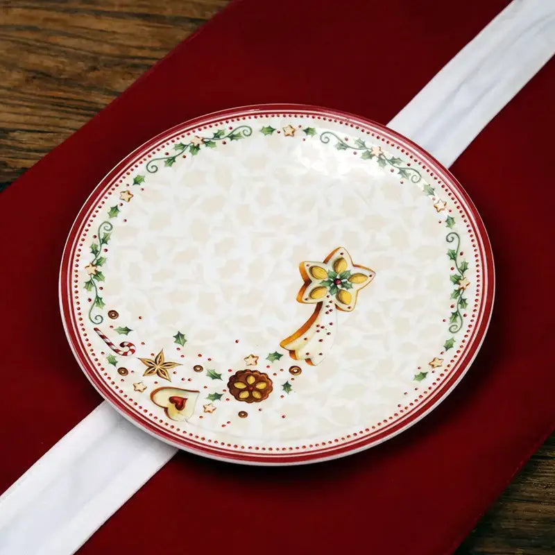 A festive cream-colored ceramic dessert plate with red rim and holly motifs from decorbites christmas porcelain tableware set
