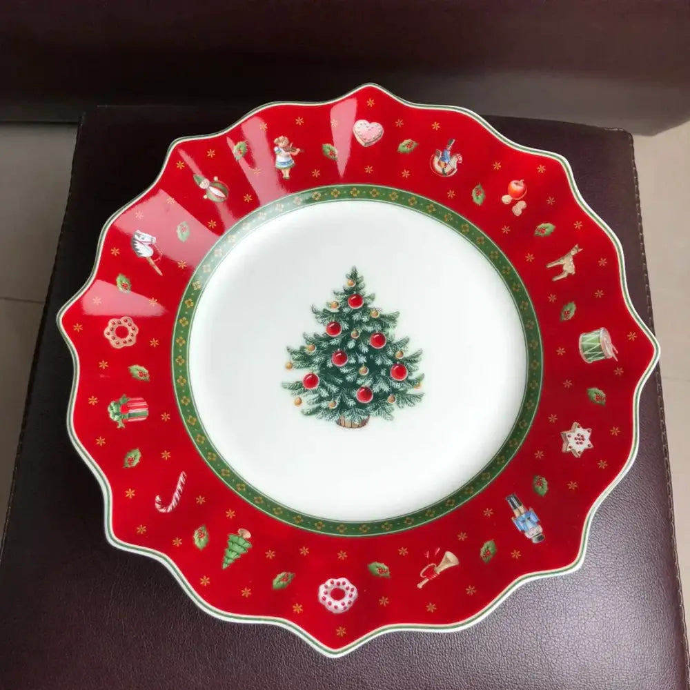A festive red ceramic plate with scalloped edge featuring a christmas tree and motifs from the decorbites christmas porcelain tableware set