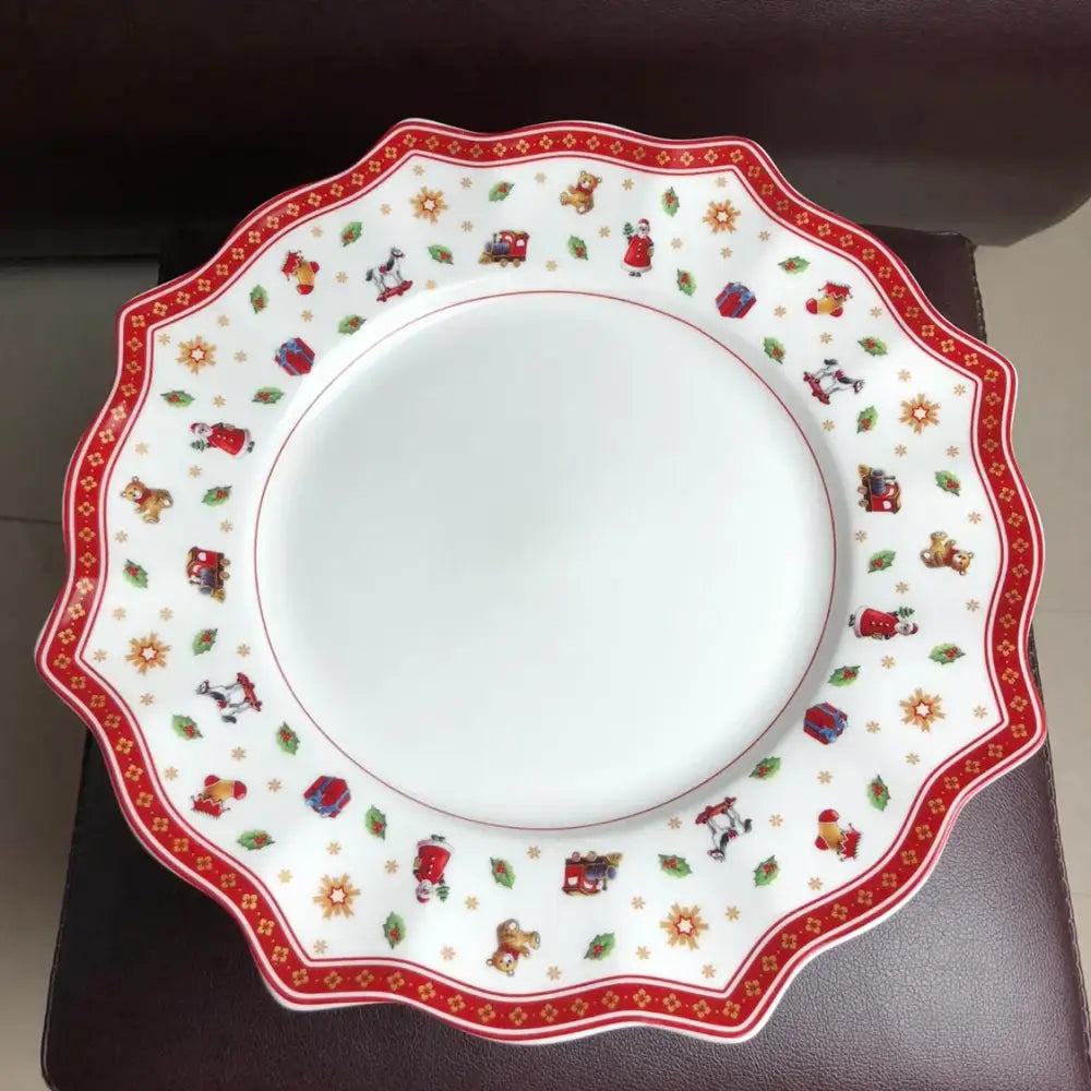 A festive white ceramic plate with scalloped edge and red gold christmas illustrations from the decorbites christmas porcelain tableware set