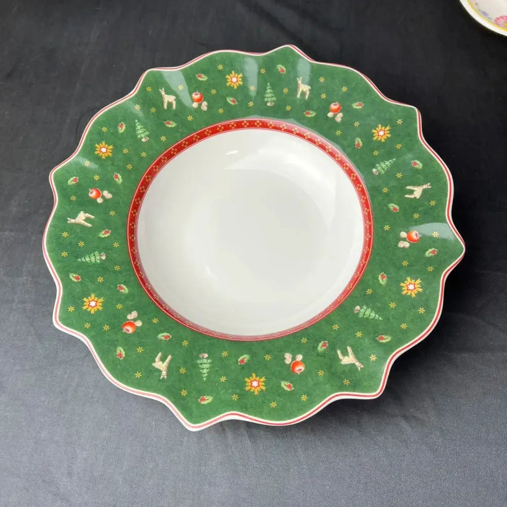 Green ceramic bowl with scalloped edges featuring white reindeer red apples and yellow flowers in decorbites christmas porcelain tableware set