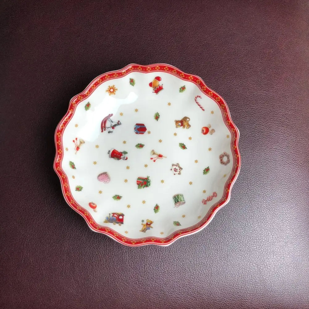 A white ceramic dish with a scalloped red rim featuring festive santa claus and holly in the decorbites christmas porcelain tableware set