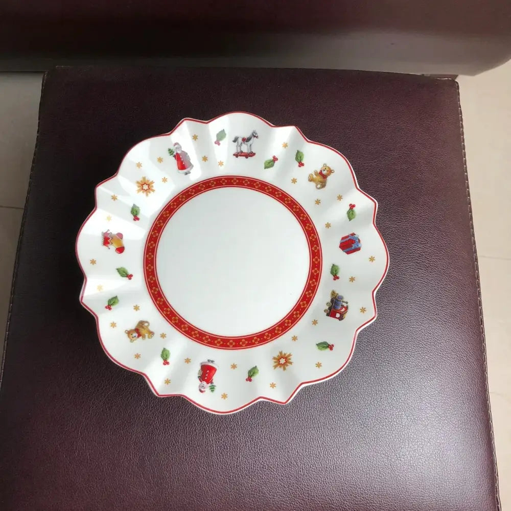 White ceramic plate with scalloped edges featuring festive red and gold holiday illustrations in DecorBites Christmas porcelain tableware set