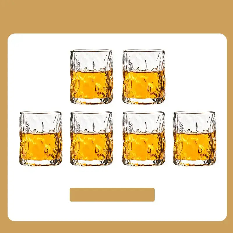 Set of six clear textured glass whiskey tumblers with amber liquid in DecorBites cups holder set for drying