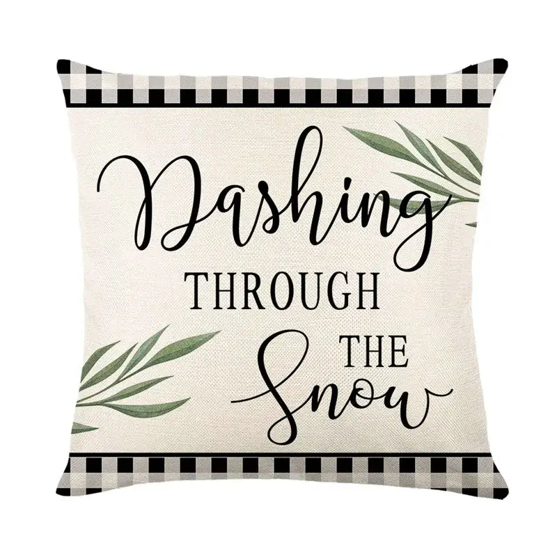 Beige pillow cover with black cursive text dashing through the snow and green leaves in a black-and-white gingham border decorbites christmas snow elk design