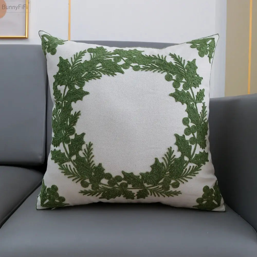 White cushion cover featuring an embroidered green holly wreath design by decorbites christmas snowflake collection