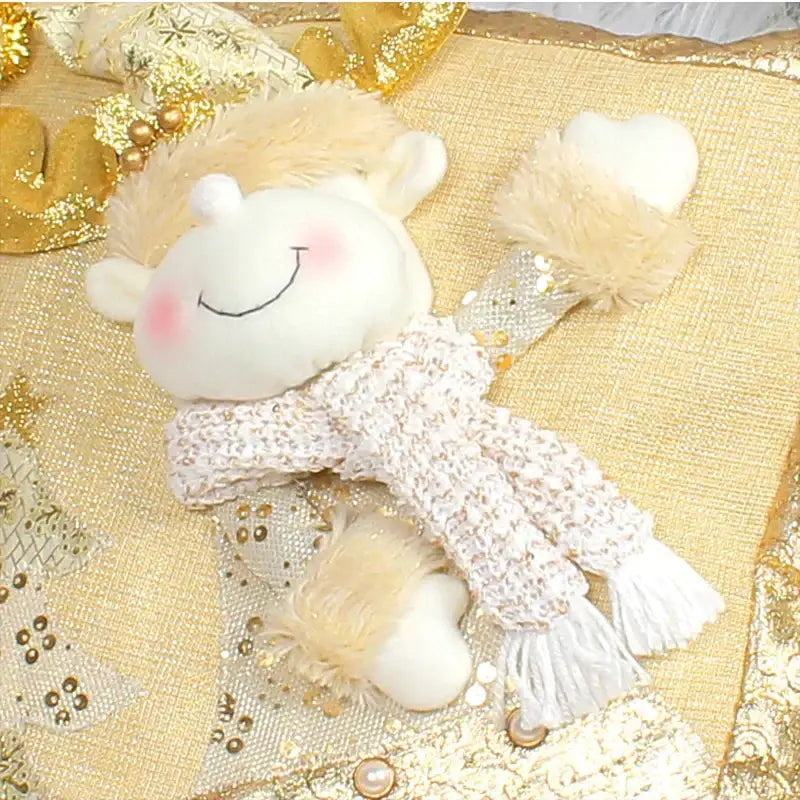 A plush white angel doll with blonde fur hair and a knitted scarf on a gold embroidered santa claus pillowcase