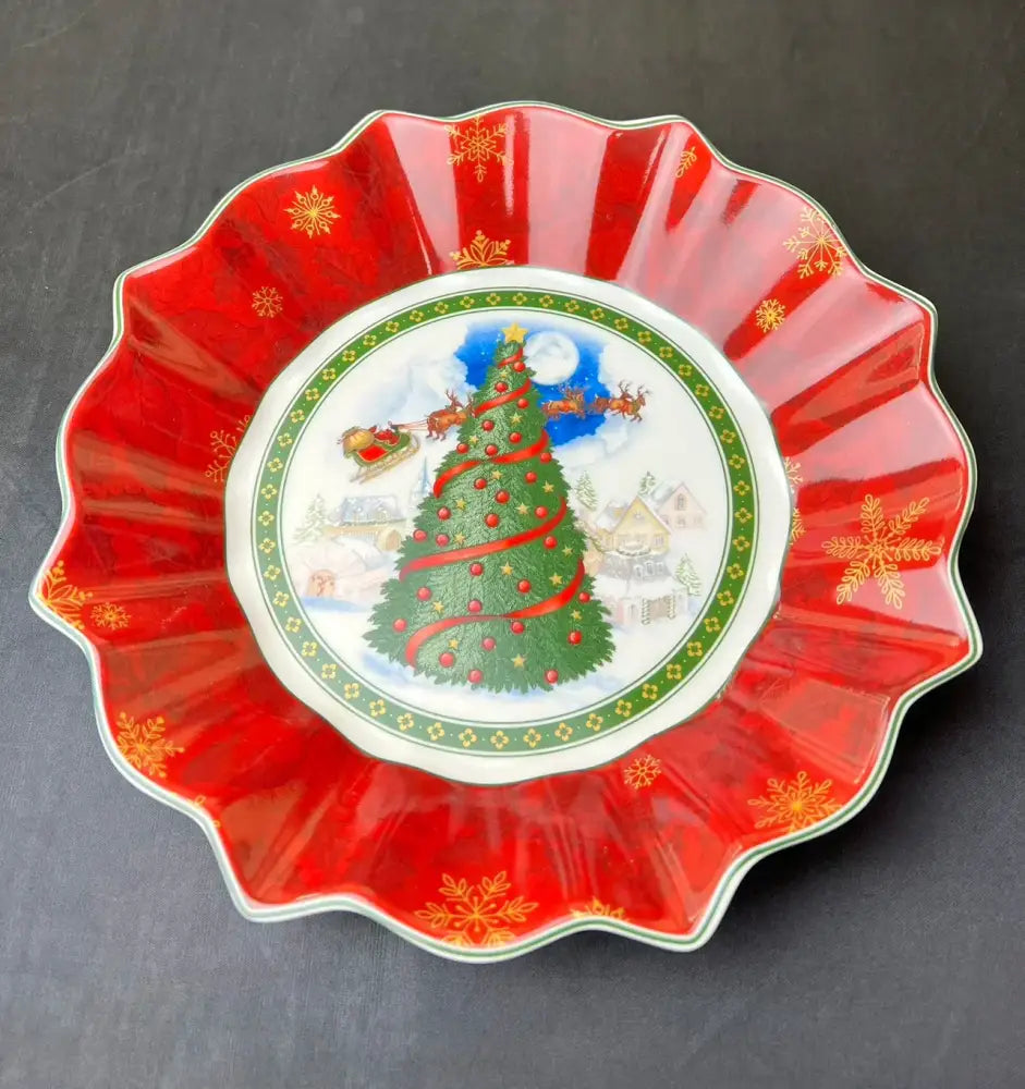 A festive red ceramic serving dish with a scalloped edge and a christmas scene in the decorbites christmas tableware set