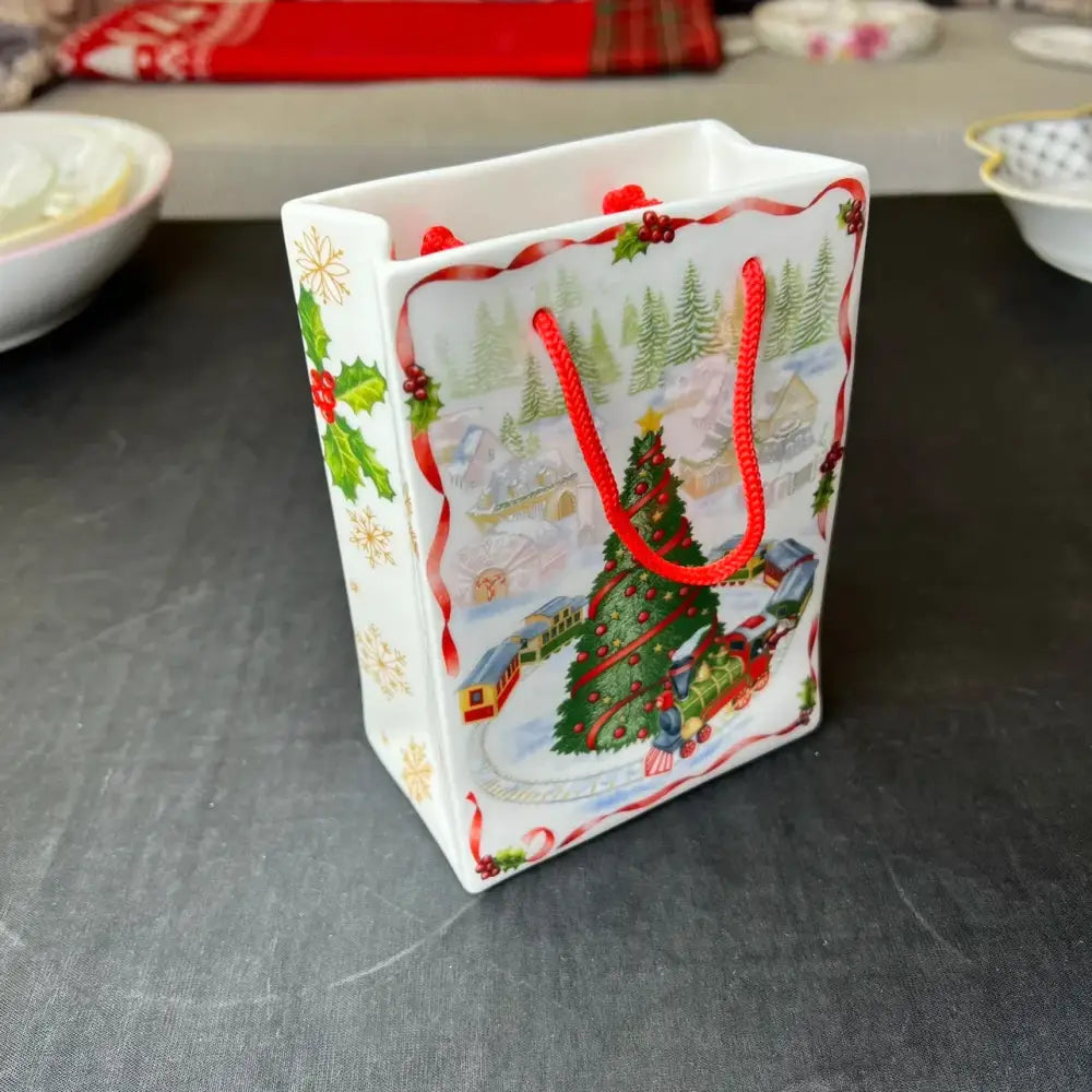White ceramic gift bag with festive christmas scene red braided handles and holly accents from DecorBites christmas tableware