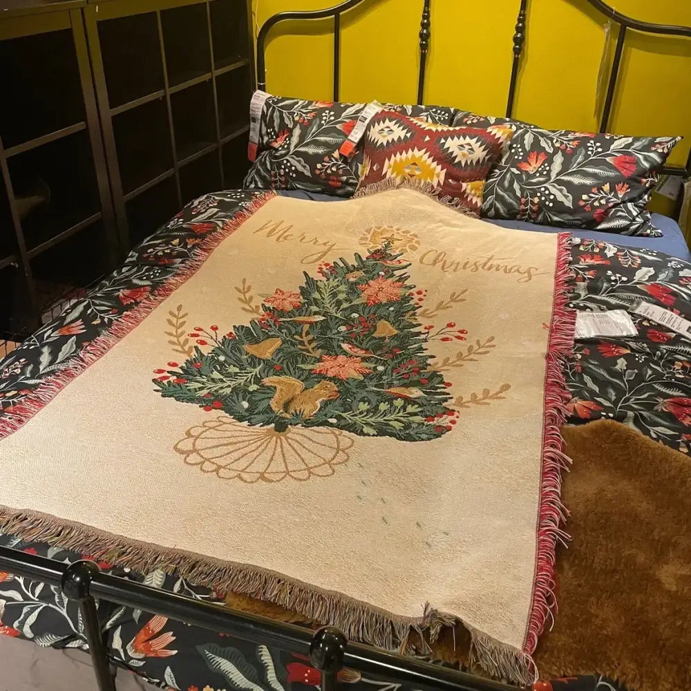 Beige woven decorbites christmas throw blanket with festive tree design, green foliage, red berries, gold accents, and fringed edges