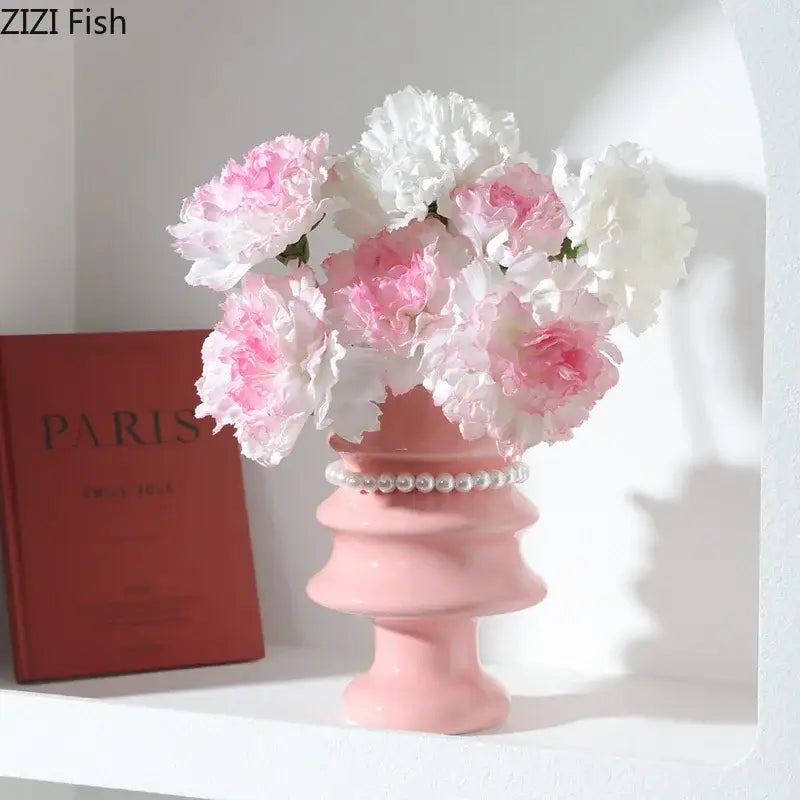 A pink decorbites christmas tree ceramic vase with pearl embellishment holding white and light pink peonies