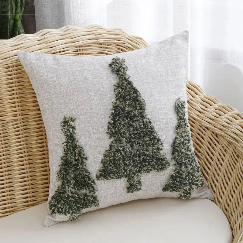 A light beige linen pillow cover with three dark green embroidered pine trees from decorbites christmas tree gold collection